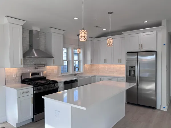 a kitchen with stainless steel appliances granite countertop a sink a stove a refrigerator and a window