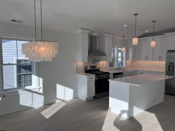 a kitchen with stainless steel appliances granite countertop a sink a stove and a wooden floors