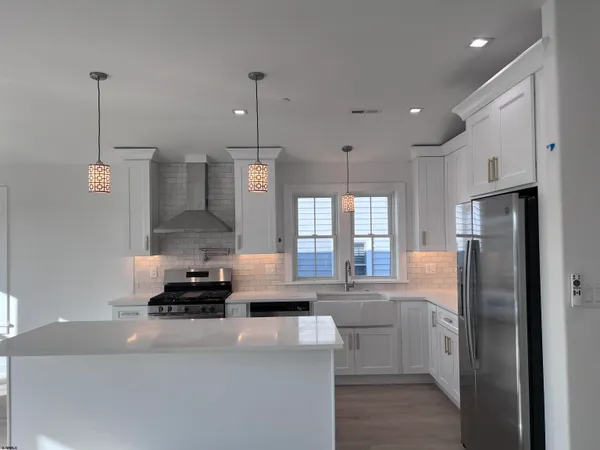 a kitchen with stainless steel appliances a refrigerator a sink a stove a microwave and wooden floor