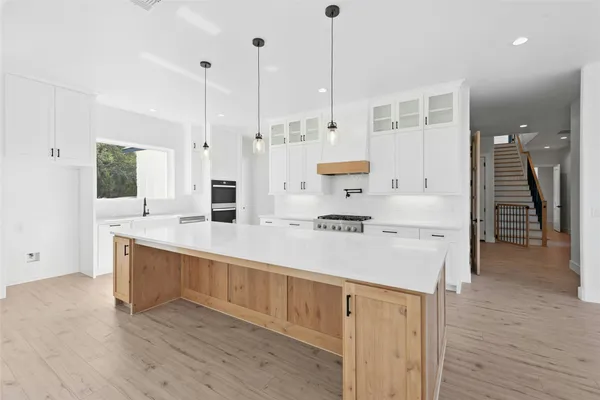 a large kitchen with kitchen island a stove a sink a center island and wooden floor