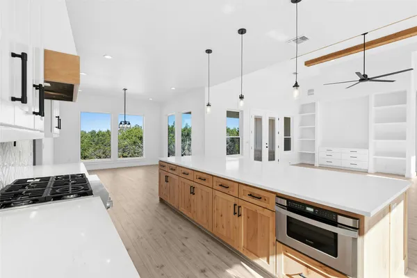 a kitchen with stainless steel appliances a stove a sink a center island and a wooden floor