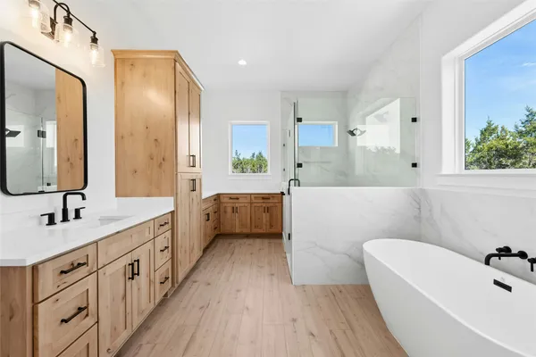 a bathroom with a double vanity sink a mirror a bathtub and shower