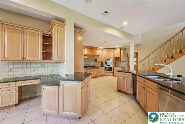 a kitchen with stainless steel appliances granite countertop a sink and dishwasher a oven with white cabinets