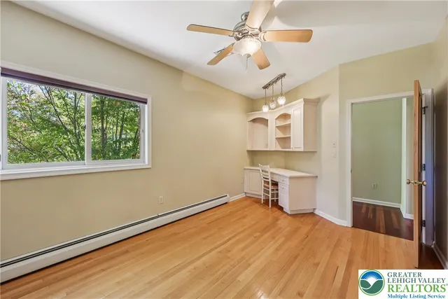 an empty room with wooden floor fan and windows
