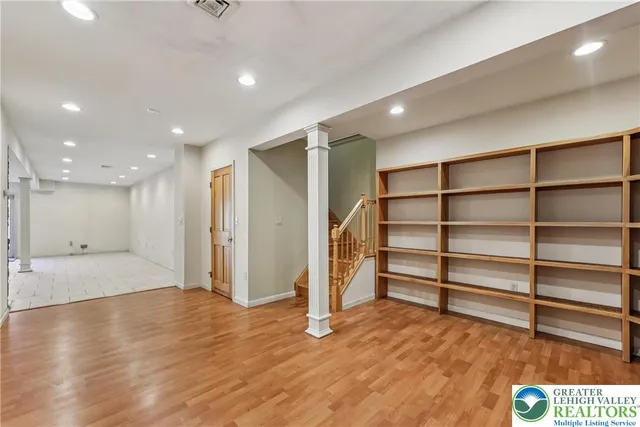 a view of an empty room with wooden floor and staircase