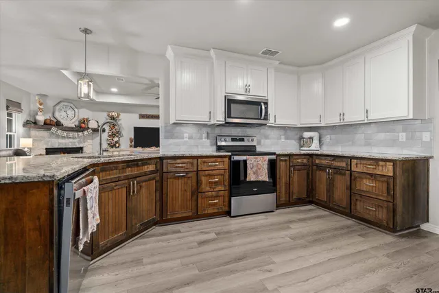 a kitchen with stainless steel appliances granite countertop a stove top oven a sink dishwasher and a microwave oven with large wooden cabinets