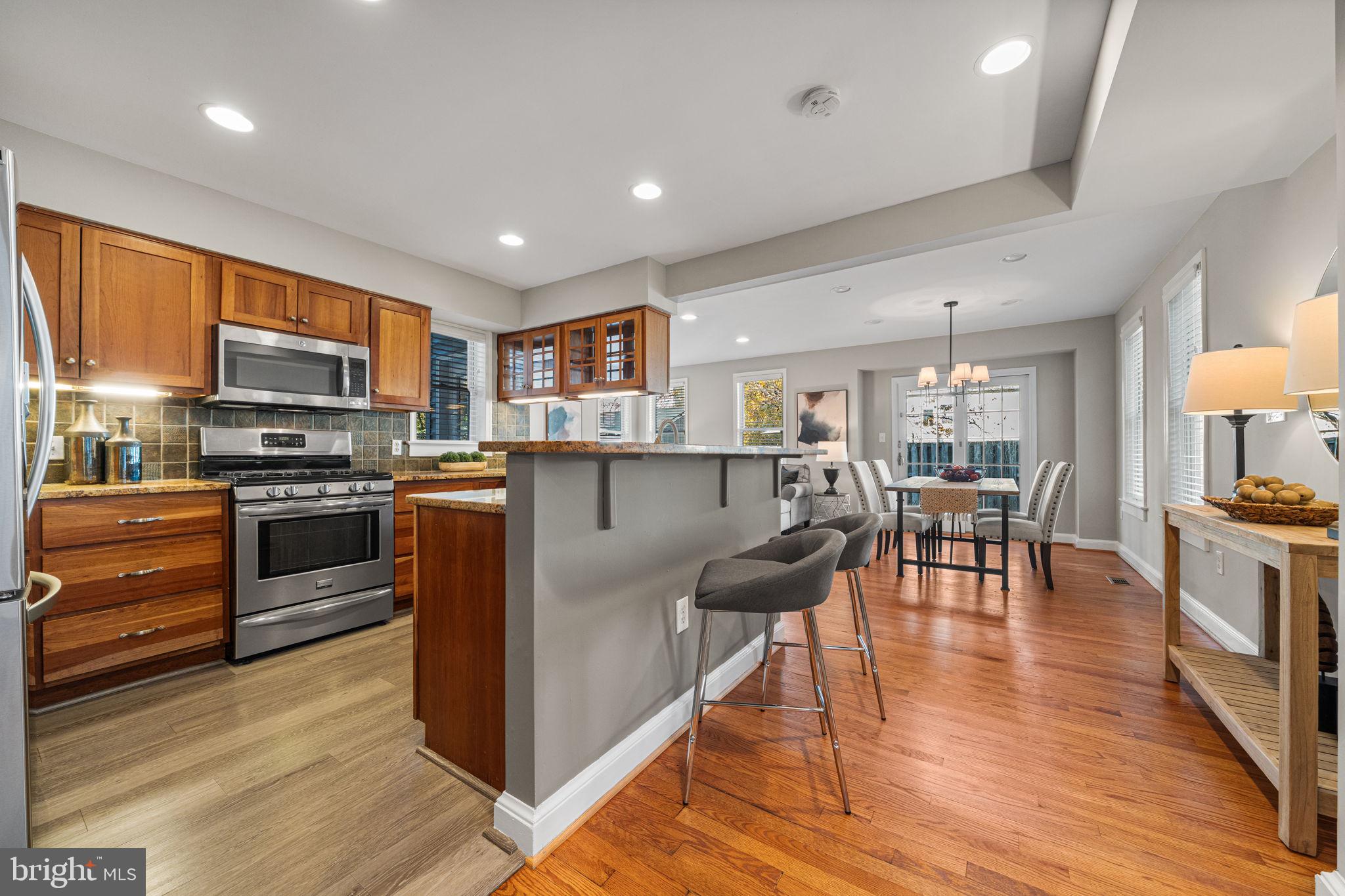 4613 8th Road South Arlington, VA 22204 - Photo 14 of 59 a kitchen with stainless steel appliances granite countertop a stove top oven a sink dishwasher a dining table and chairs with wooden floor