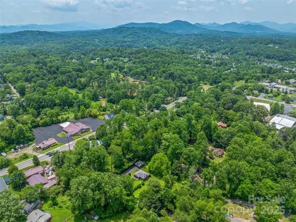 a view of a lush green forest with a house