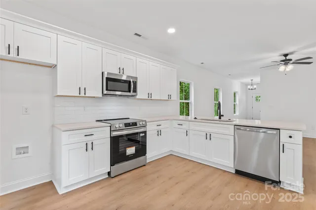 a kitchen with granite countertop white cabinets and stainless steel appliances