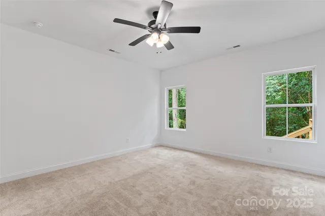 an empty room with windows and chandelier fan