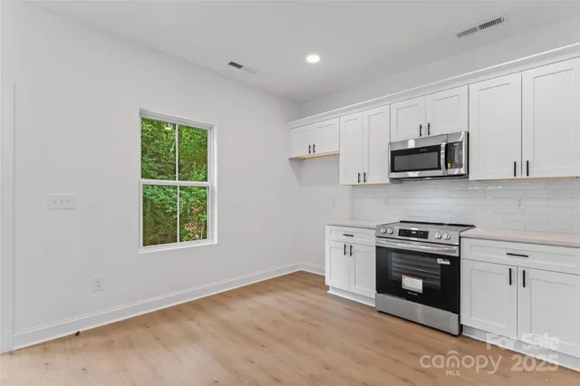 a kitchen with stainless steel appliances white cabinets and a stove top oven