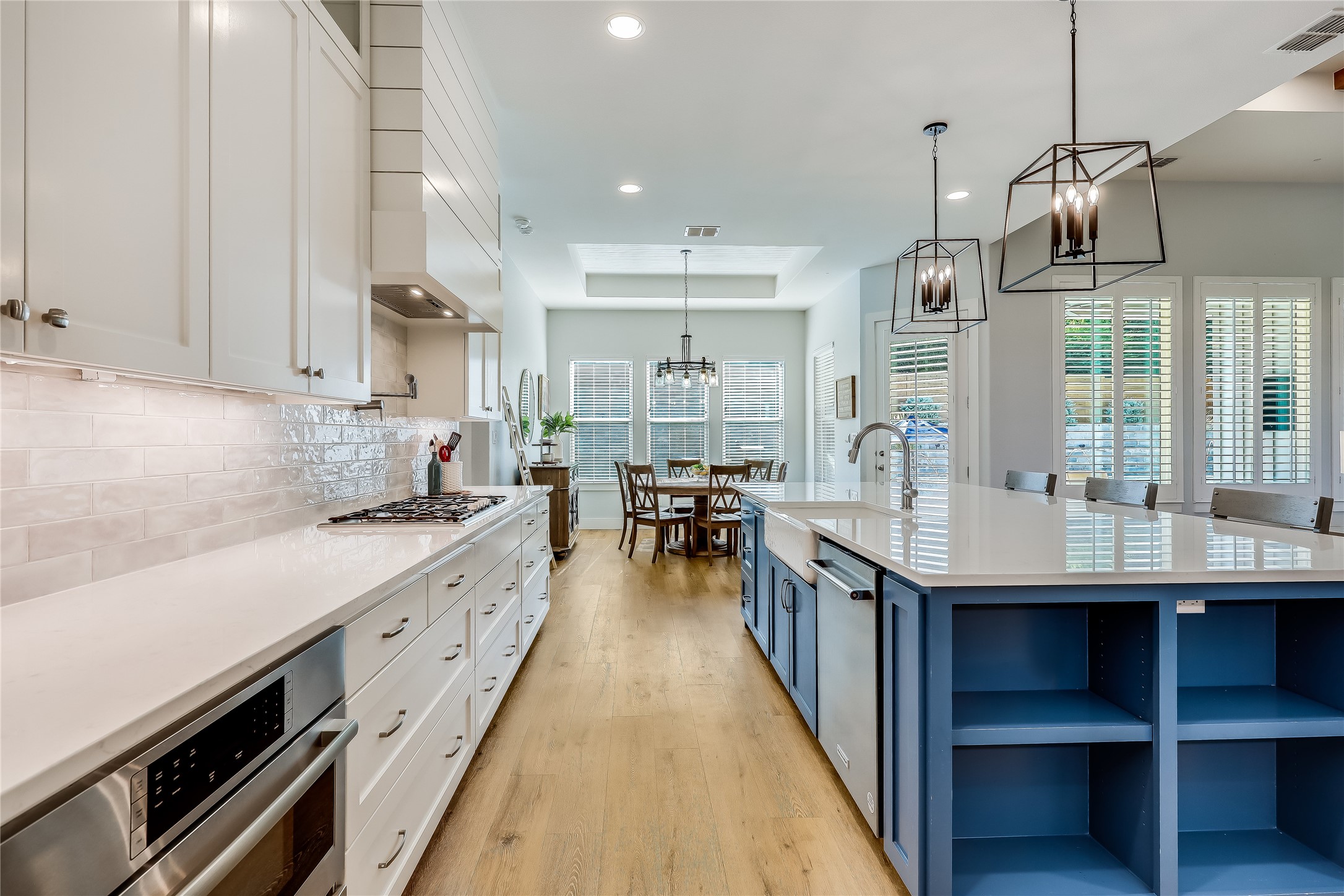 233 Lakefront Drive Lago Vista, TX 78645 - Photo 8 of 40 Kitchen with white Shaker cabinets, a raised ceiling, stainless steel appliances, farm sink, quartz counter tops, open shelves on island, a pot filler at the chef style range, warming drawer and designer light fixtures