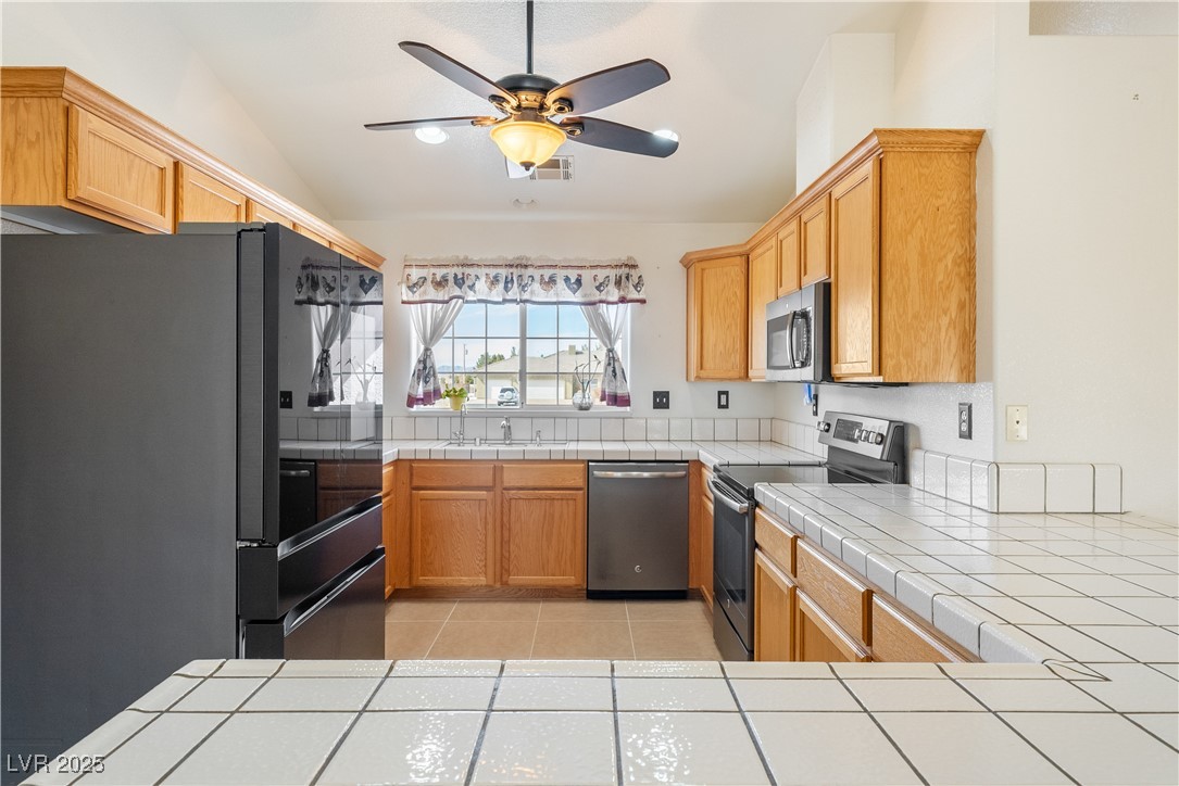 3581 Ranger Way Pahrump, NV 89048 - Photo 5 of 57 Kitchen with appliances with stainless steel finishes, light tile patterned flooring, vaulted ceiling, and tile countertops