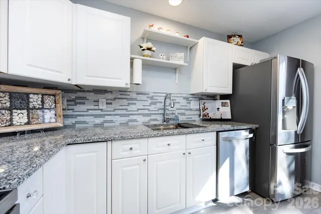 a kitchen with granite countertop a sink a refrigerator and a stove