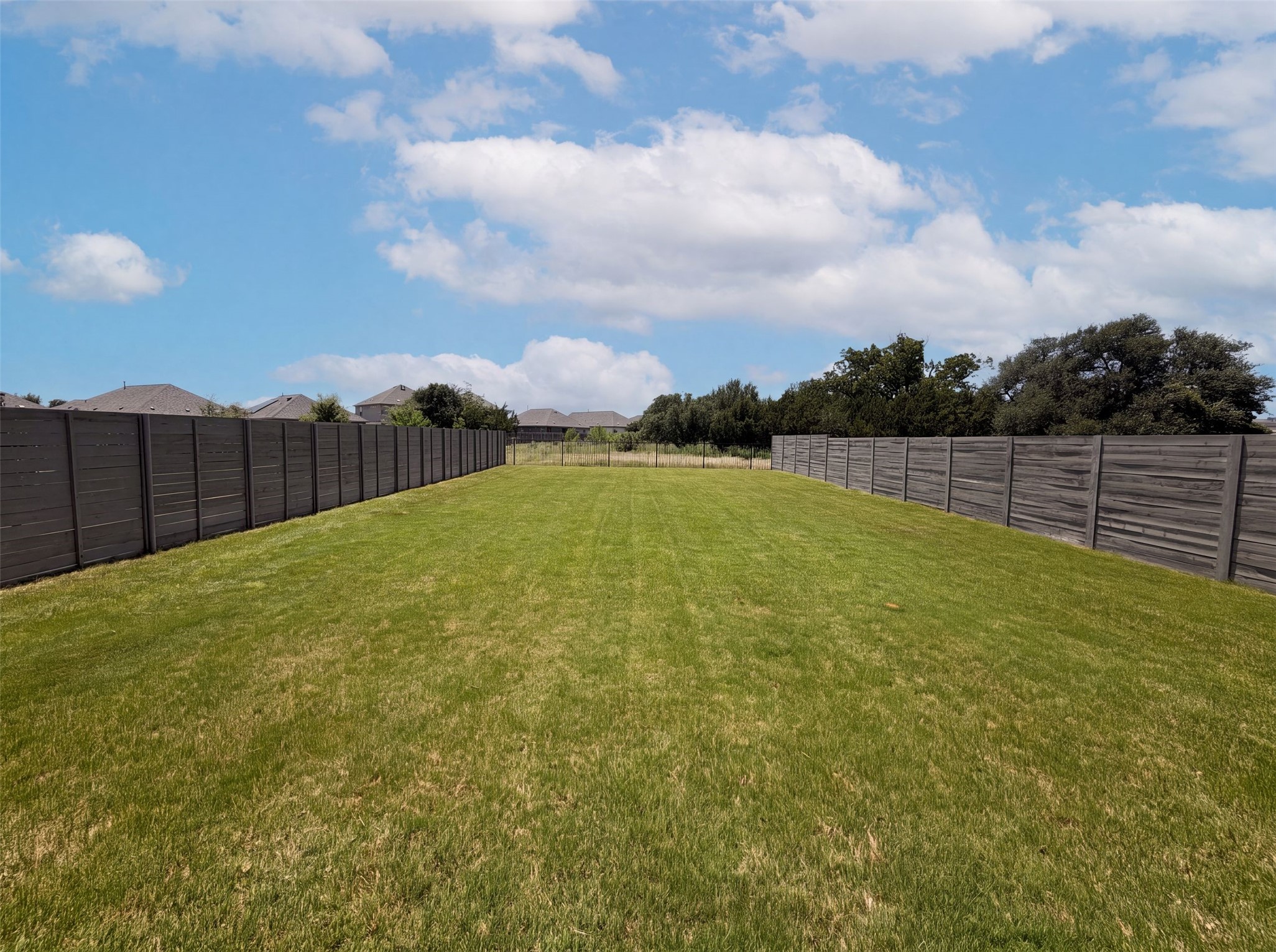 424 Wolf Springs Road Georgetown, TX 78628 - Photo 15 of 15 A spacious, manicured yard offers ample room for outdoor activities, bordered by tasteful fencing and distant homes.