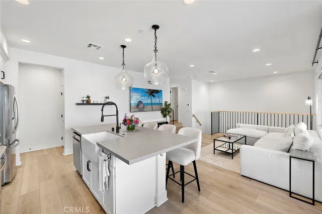 a kitchen with stainless steel appliances a stove a sink a refrigerator and white cabinets with wooden floor