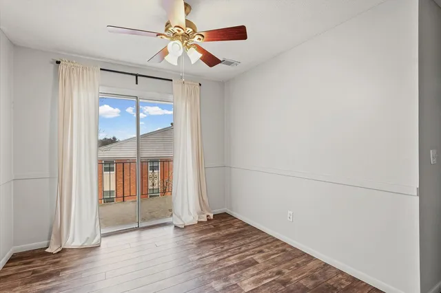 a view of an empty room with window and wooden floor