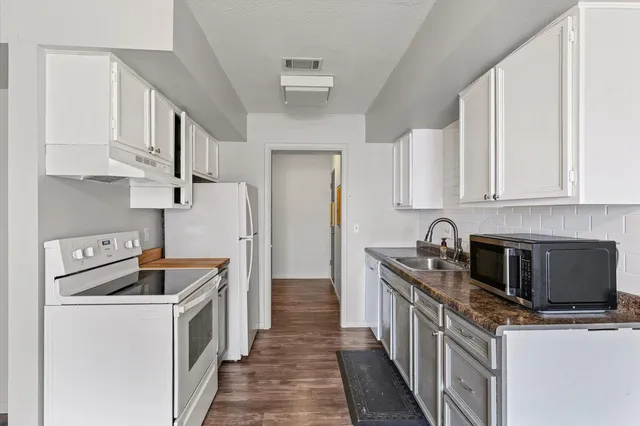 a kitchen with stainless steel appliances granite countertop a stove a sink dishwasher and a refrigerator with wooden cabinets