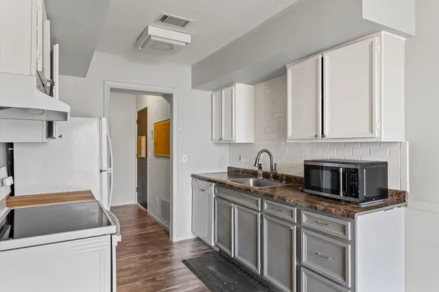 a kitchen with stainless steel appliances granite countertop a stove a sink and a refrigerator with white cabinets