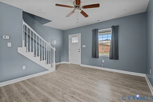 a view of an empty room with wooden floor and a window