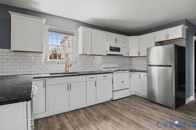 a kitchen with stainless steel appliances granite countertop a refrigerator sink and white cabinets