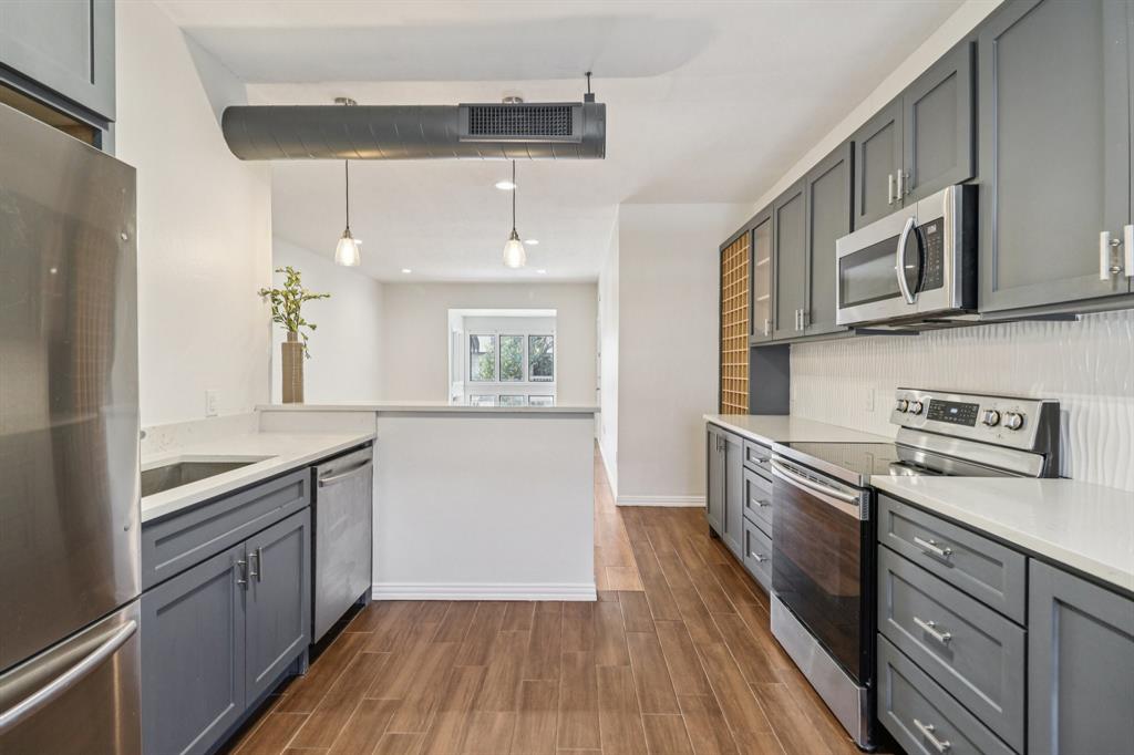 10754 Villager Road, Unit D Dallas, TX 75230 - Photo 5 of 37 a kitchen with stainless steel appliances granite countertop a sink and wooden cabinets