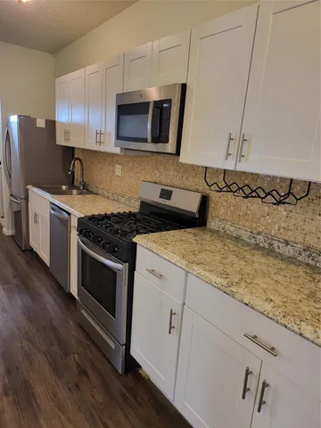 a kitchen with stainless steel appliances granite countertop a stove a microwave and wooden cabinets