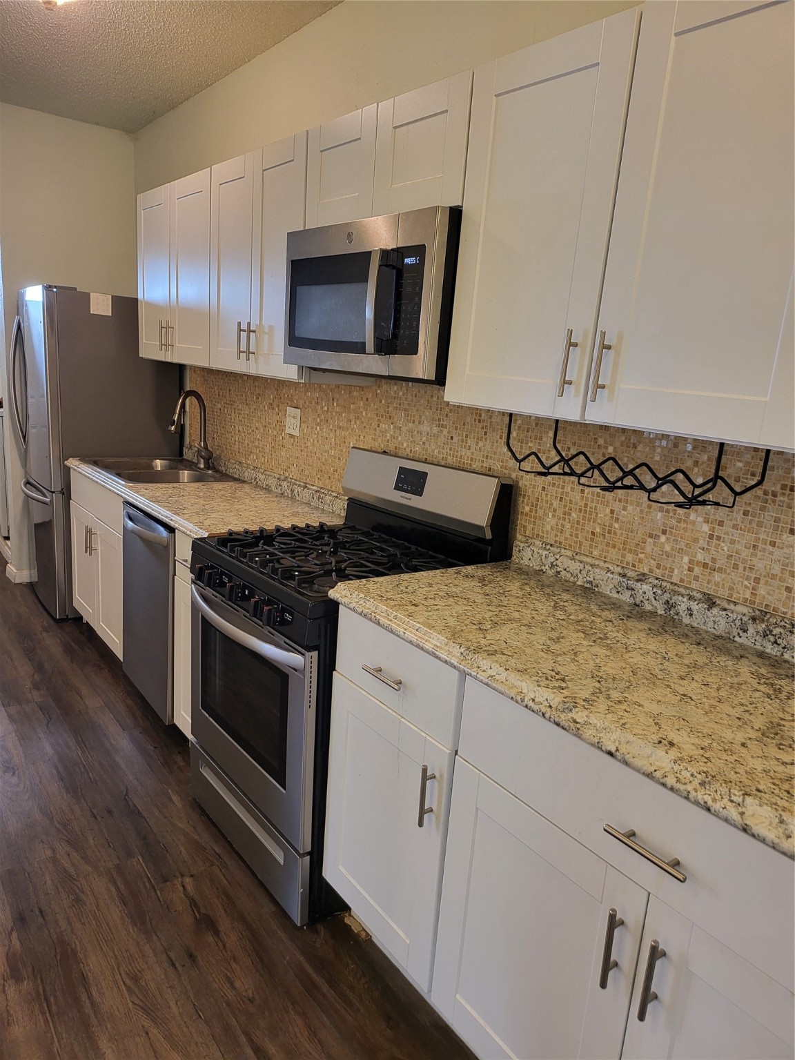 a kitchen with stainless steel appliances granite countertop a stove a microwave and wooden cabinets