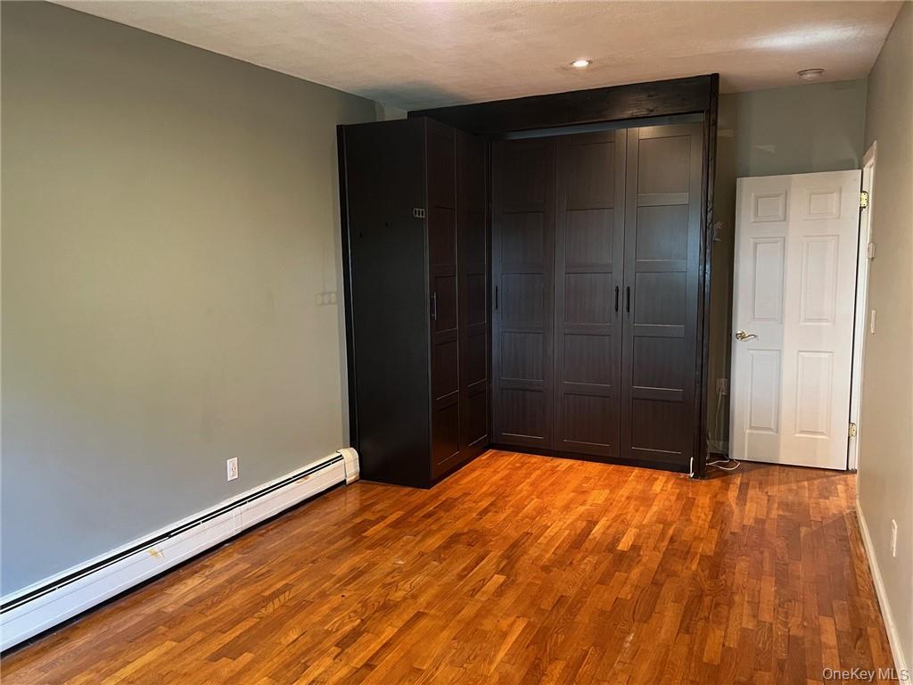 708 Silver Lake-Scotchtown Road Middletown, NY 10941 - Photo 22 of 25 Unfurnished bedroom featuring a closet, baseboard heating, light wood-type flooring, and a textured ceiling