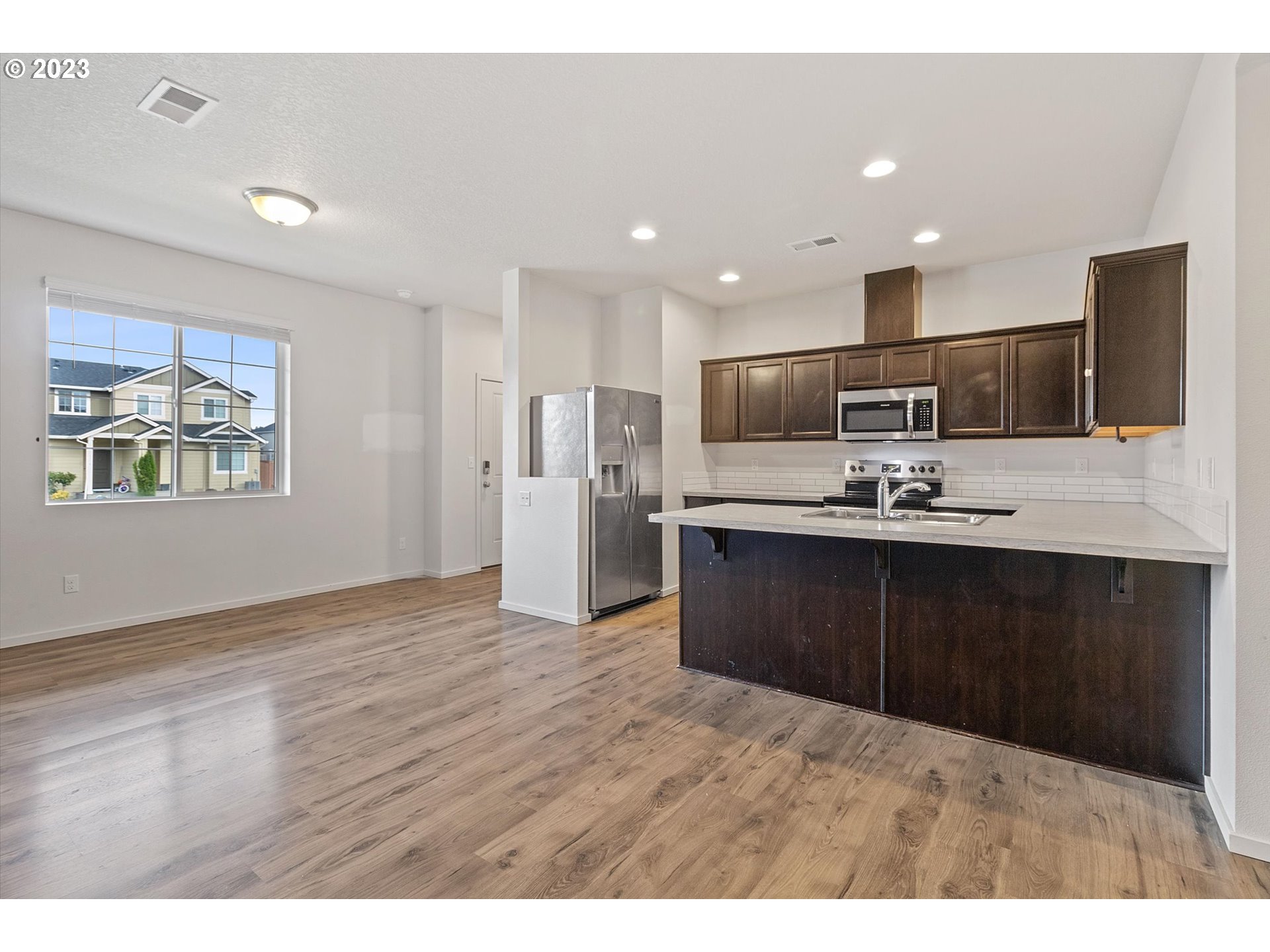 2240 Southeast 16th Street Gresham, OR 97080 - Photo 5 of 36 a kitchen with stainless steel appliances kitchen island granite countertop a refrigerator a stove a microwave oven with wooden floor