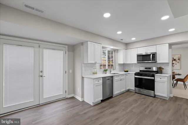 a kitchen with stainless steel appliances granite countertop a stove top oven sink and white cabinets