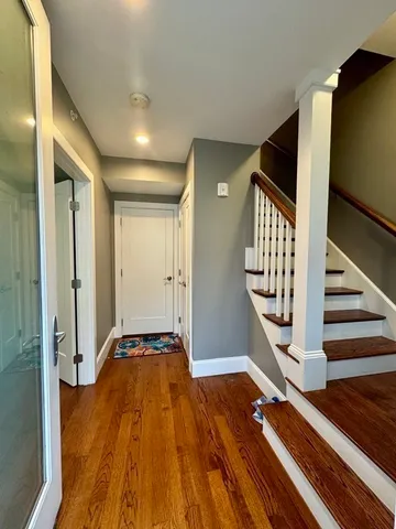 a view of a hallway with wooden floor and staircase