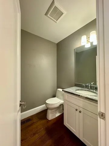 a bathroom with a granite countertop toilet a sink and a mirror
