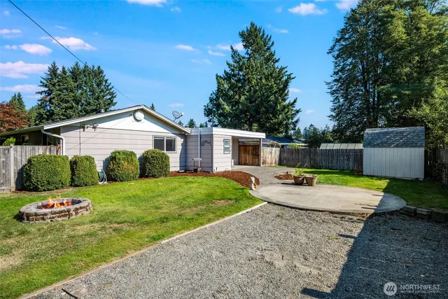 a view of a backyard with table and chairs plants and large tree
