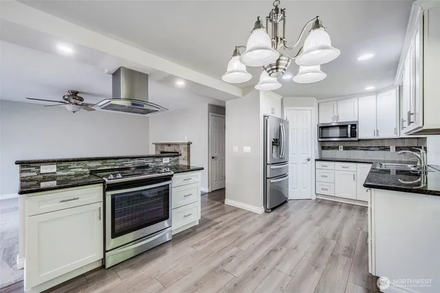 a kitchen with stainless steel appliances a stove a sink and white cabinets