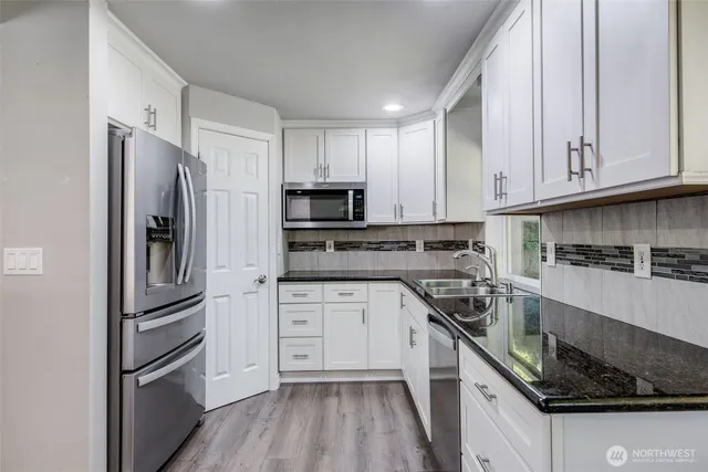 a kitchen with white cabinets stainless steel appliances and a sink