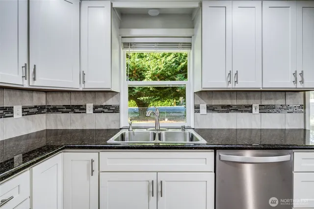 a kitchen with stainless steel appliances granite countertop a sink a stove and white cabinets