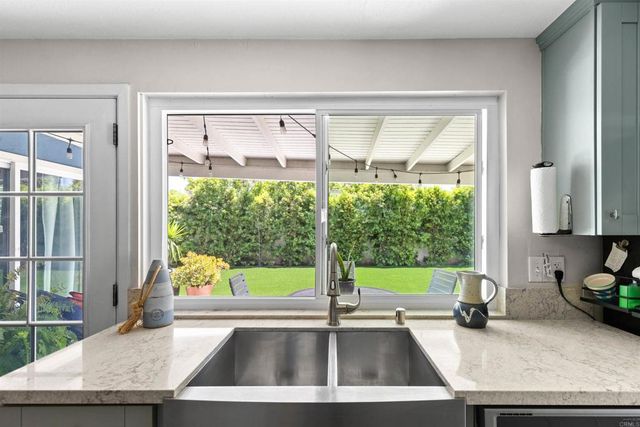 a kitchen with a sink a counter top and a view of living room