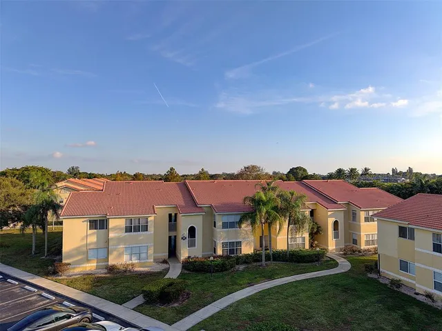 a view of a big house with a big yard plants and large tree