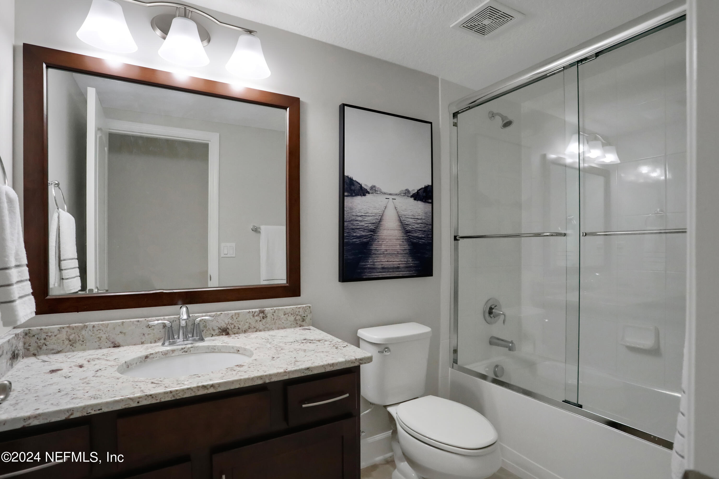 183 Flora Lake Circle St. Augustine, FL 32095 - Photo 39 of 40 a bathroom with a granite countertop sink toilet a mirror a vanity and shower