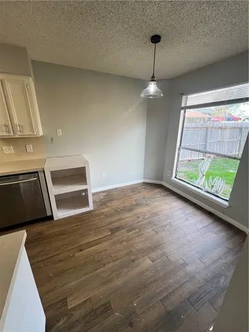 a view of an empty room with wooden floor fridge and a window