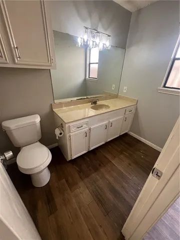 a bathroom with a granite countertop sink a toilet a mirror and vanity