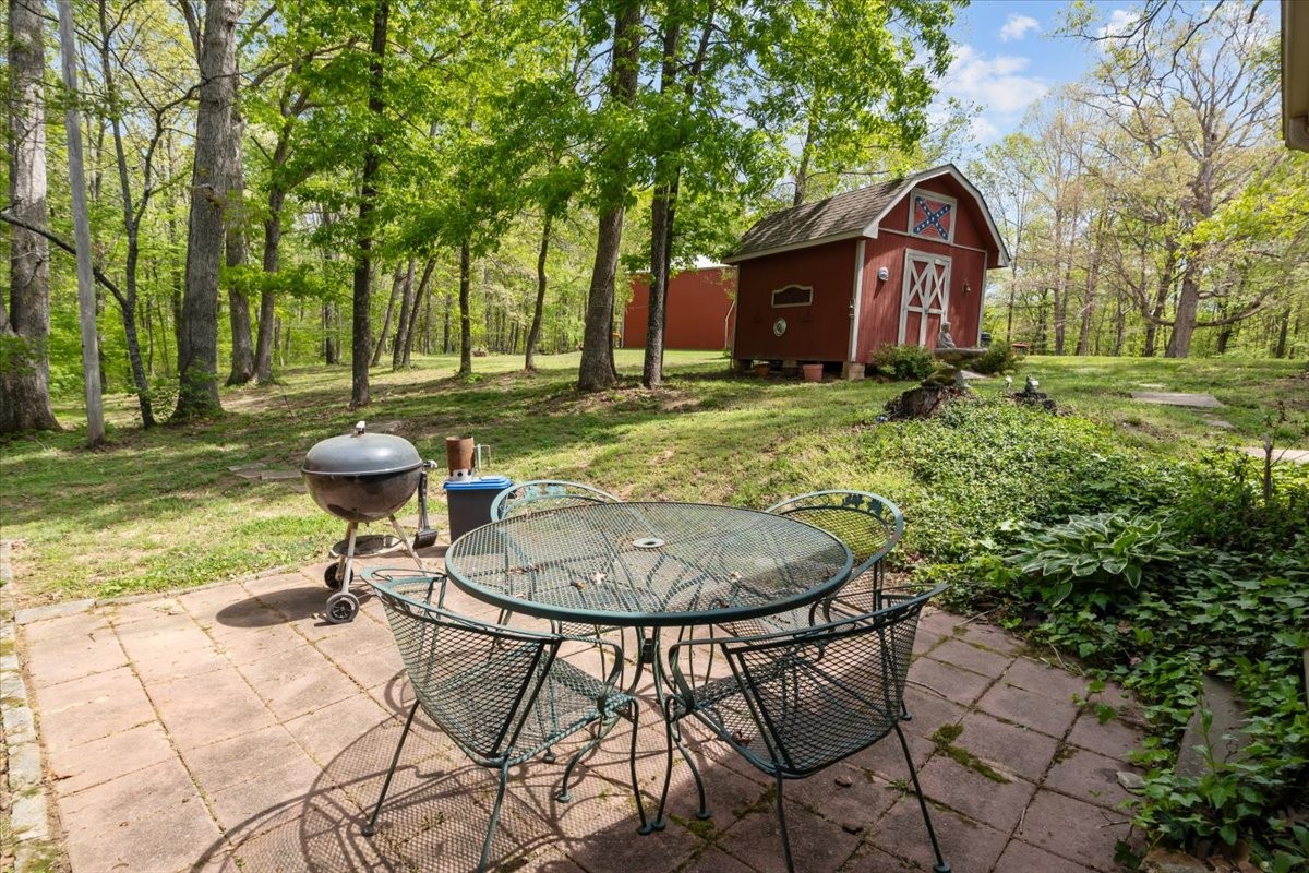 48 Hill Road Big Sandy, TN 38221 - Photo 31 of 54 a view of a backyard with table and chairs and potted plants and large trees