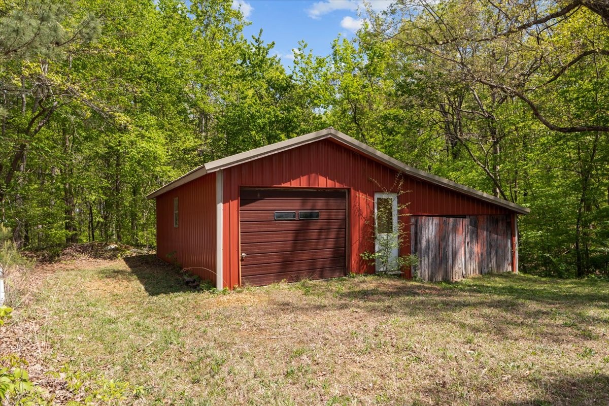 48 Hill Road Big Sandy, TN 38221 - Photo 44 of 54 a wooden house with large trees and wooden fence