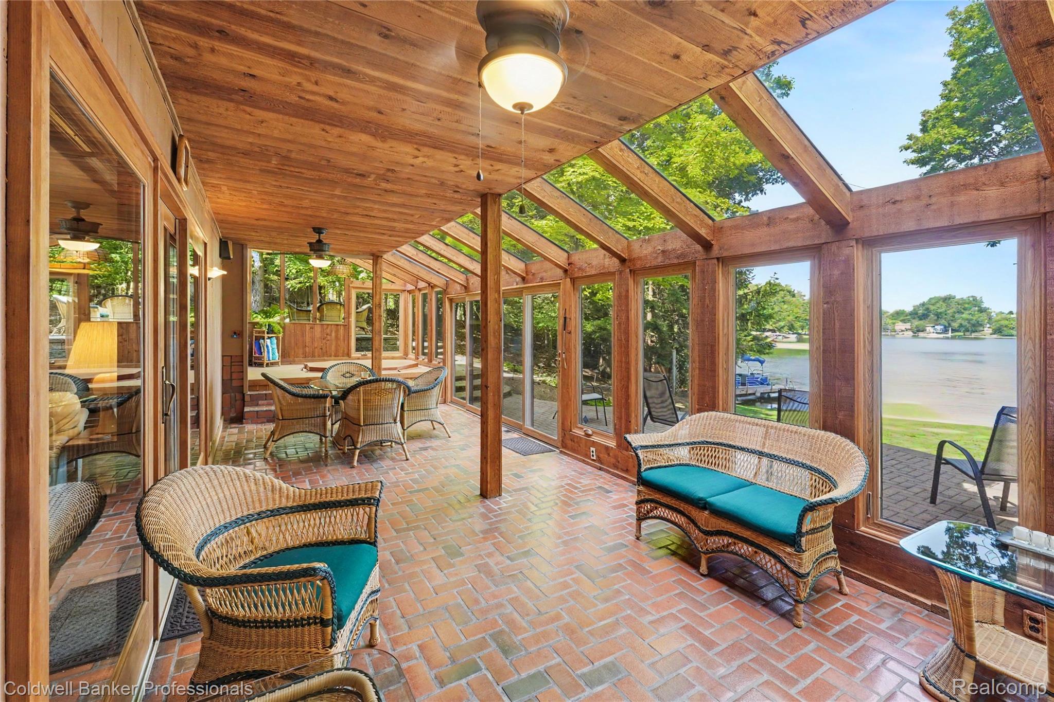 3583 Mitchell Road Metamora, MI 48455 - Photo 27 of 58 Sunroom featuring a wood-panel ceiling with integrated skylights, full-height windows, a brick-pattern floor, and a direct water frontage