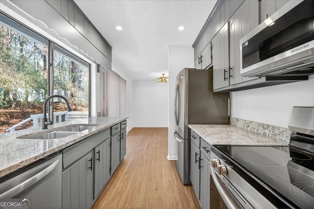 a kitchen with stainless steel appliances granite countertop a sink a stove and a refrigerator