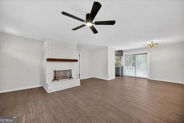a view of an empty room with wooden floor and a fireplace