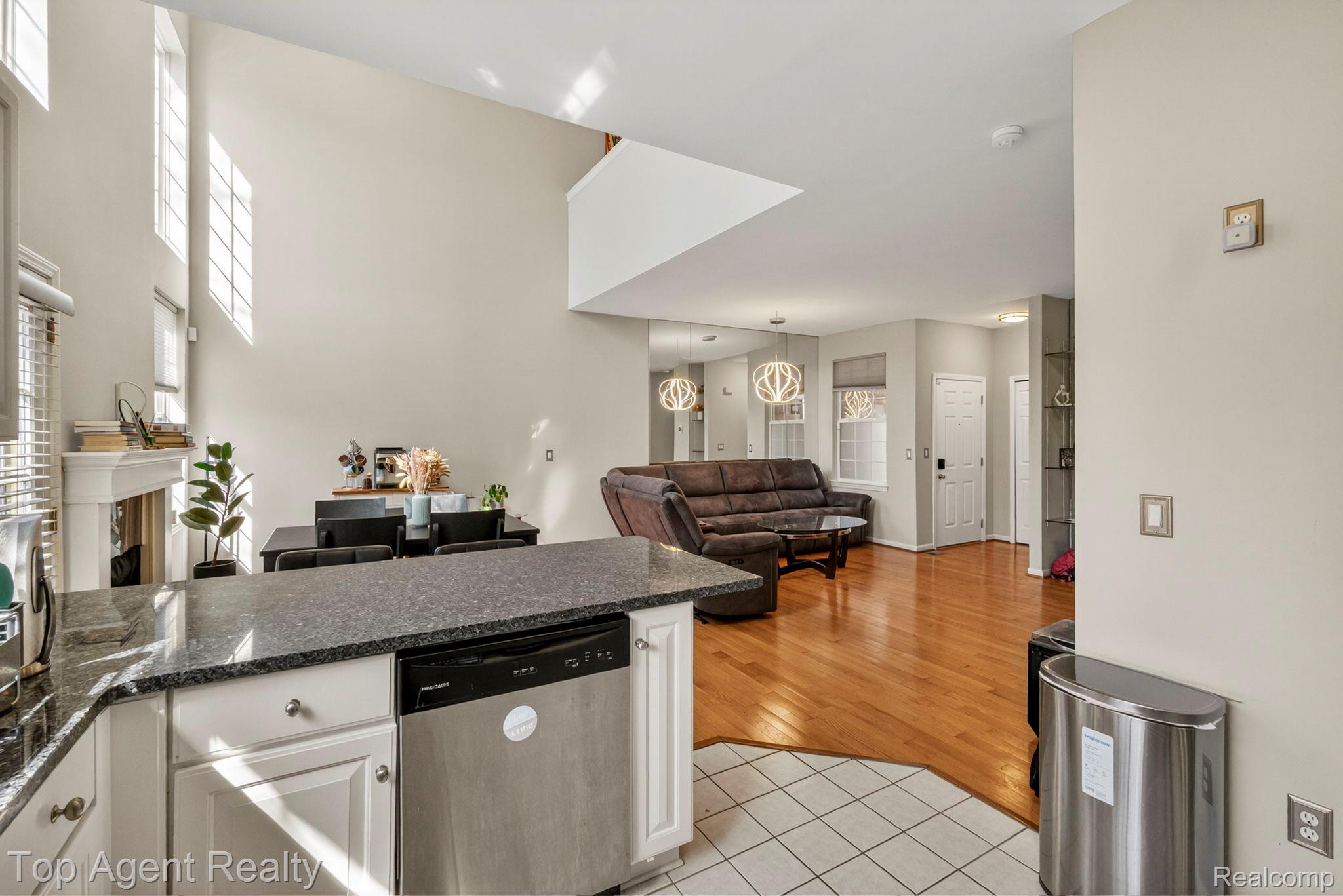 41567 Glade Road, Unit 20 Canton, MI 48187 - Photo 45 of 47 Kitchen with a peninsula, open floor plan, stainless steel dishwasher, a fireplace, and white cabinetry