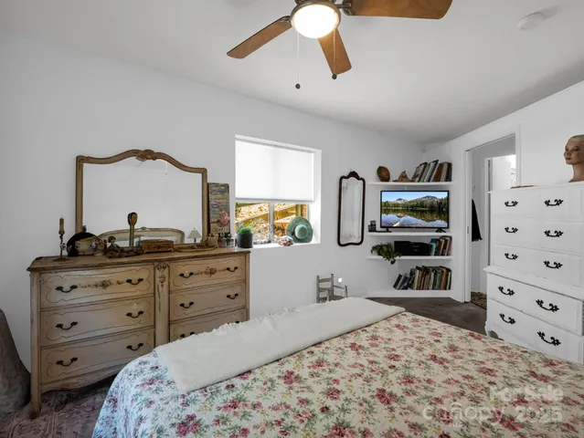 a bedroom with a bed and a flat tv screen on dresser