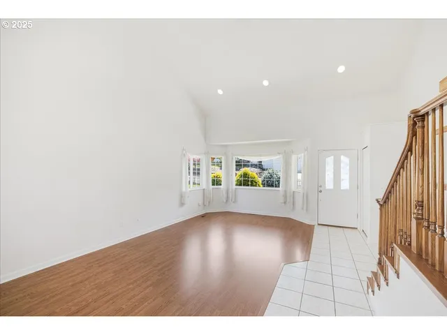 a view of an empty room and stairs with wooden floor